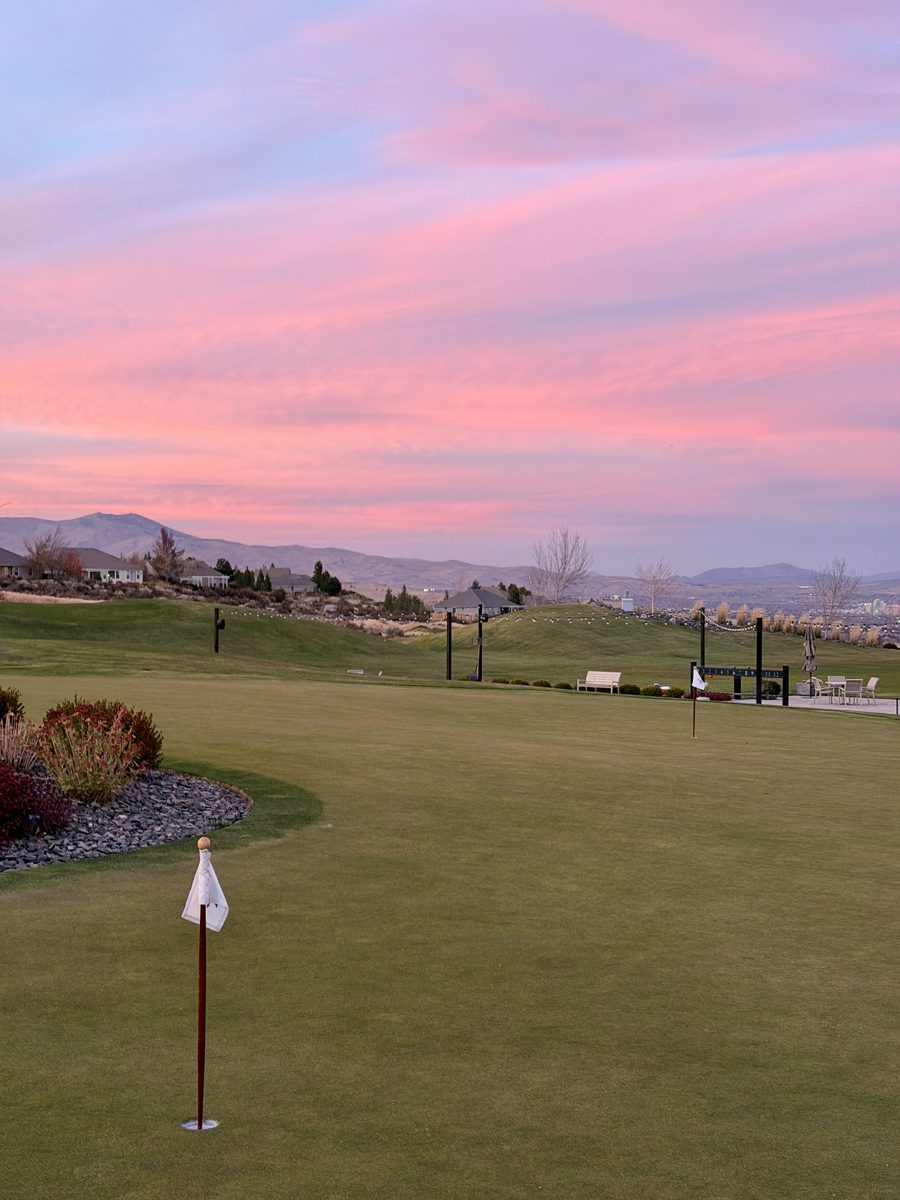A putting green at sunset with mountains behind it